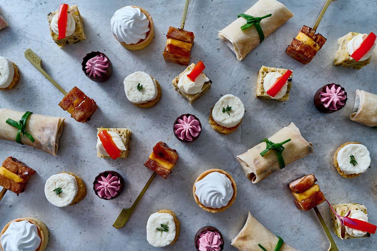 Image displays small food items from Eden Caterers, including canapés, small wraps, and small meringue desserts.