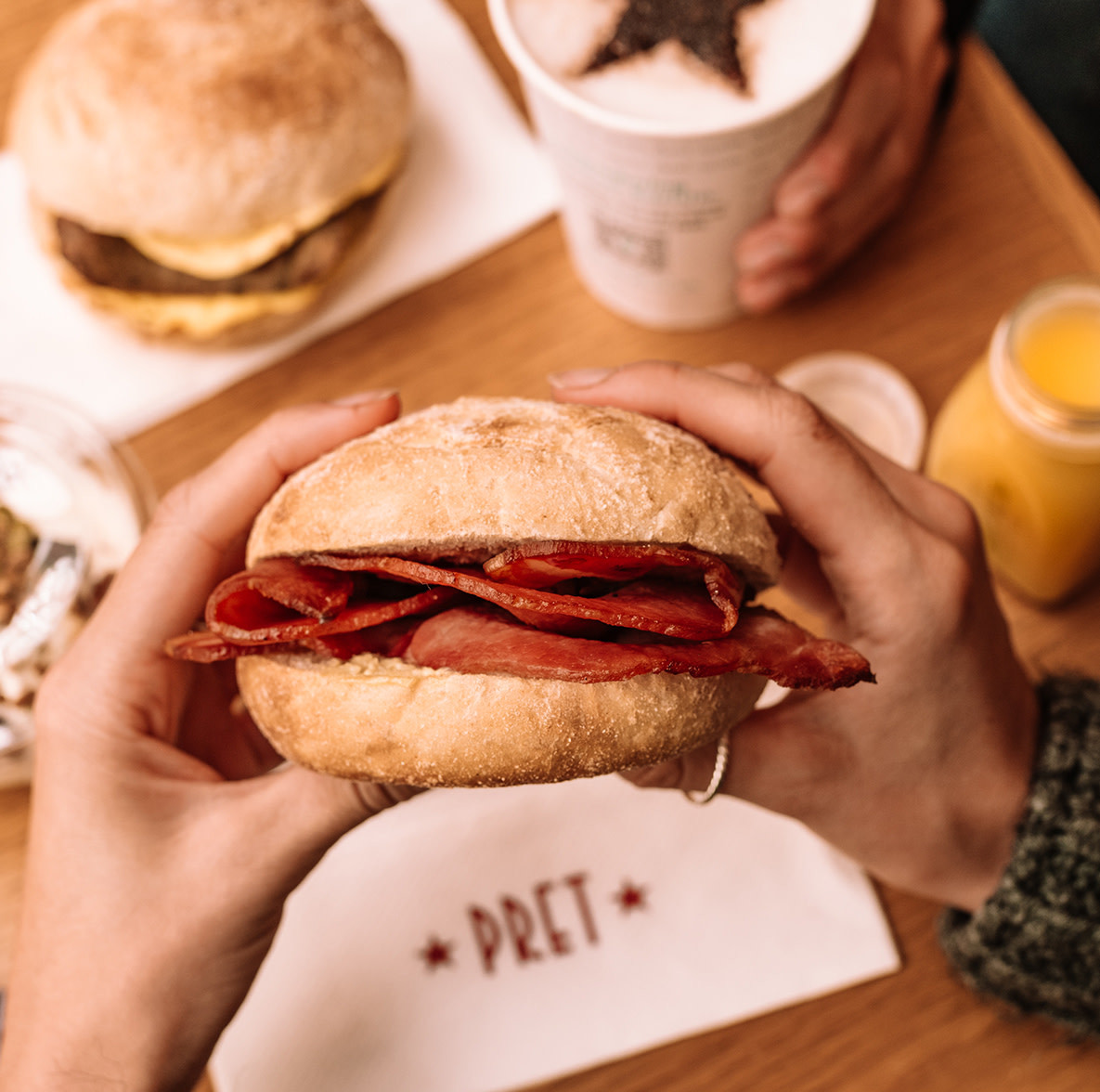 Person eating Pret bacon batch with orange juice and coffee