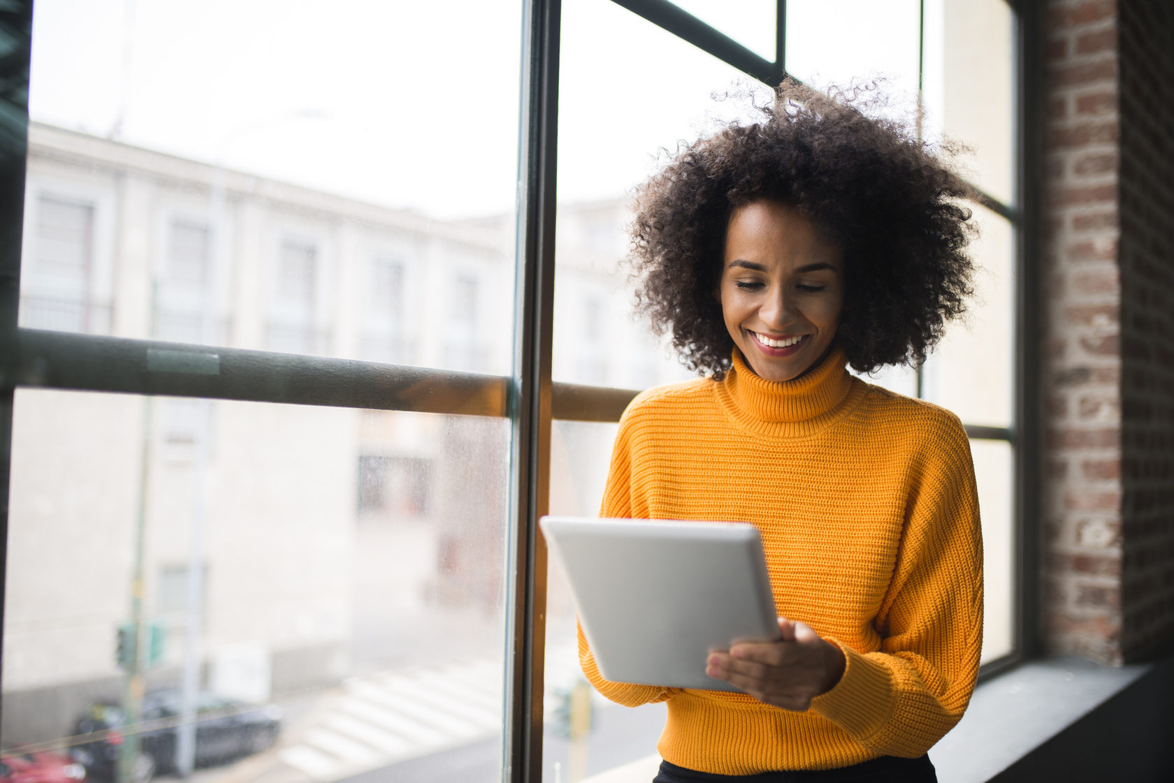 woman stands at window with tablet